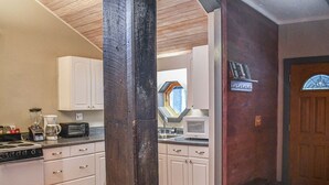 A kitchen with white cabinets, a stove, a microwave, and a coffee maker. - Brook Road Cabin (Goshen)