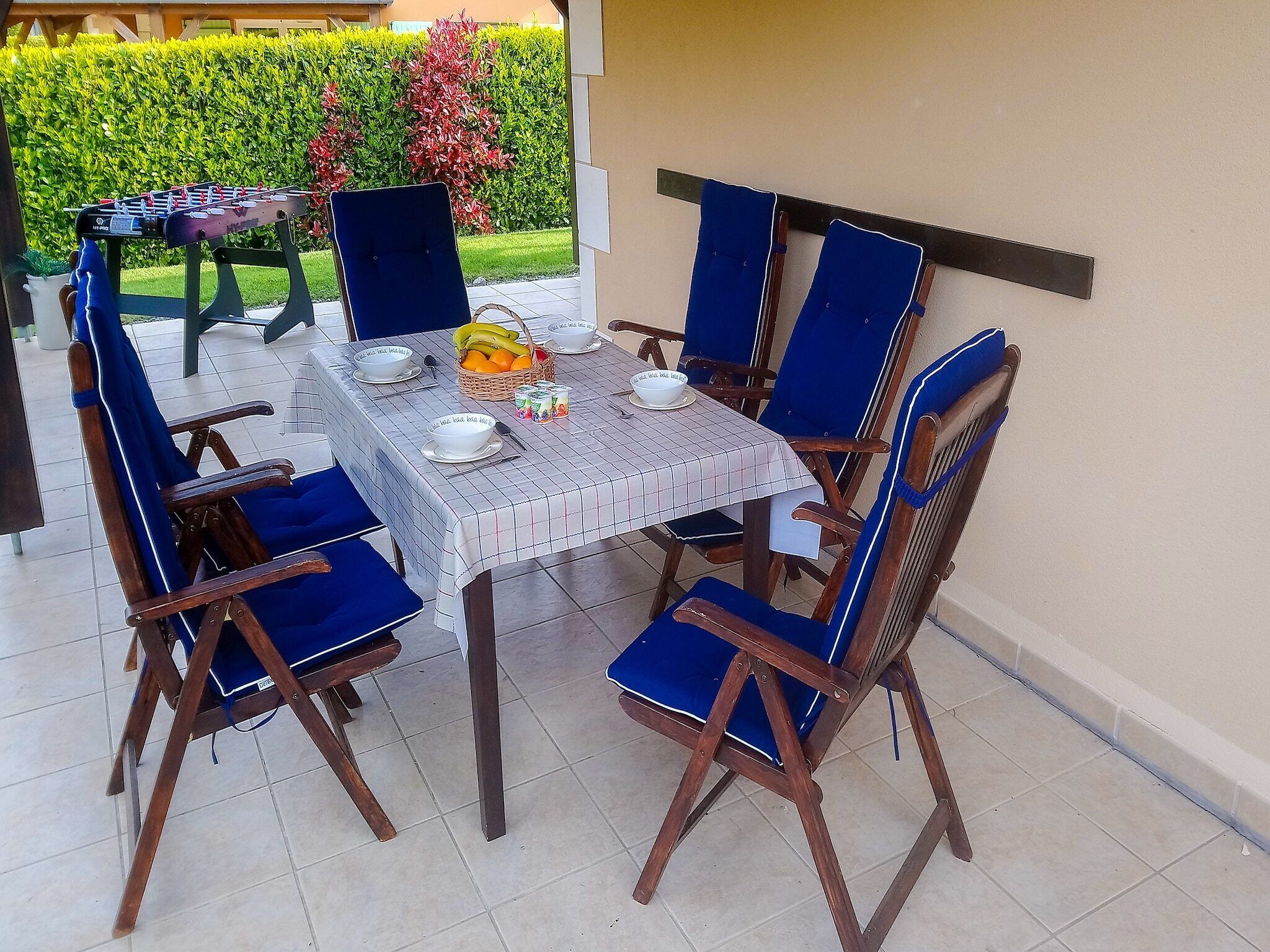 Uma mesa de jantar com toalha xadrez, rodeada por cadeiras estofadas em azul.