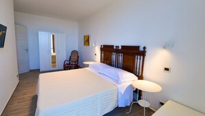 A bedroom with a large bed, a chair, a small table, and a wardrobe. - La Riggiola (Salerno)