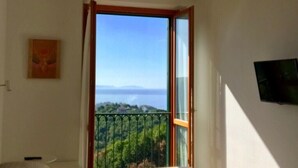 A bedroom with a large bed, a television mounted on the wall, and a balcony with a scenic view. - La Riggiola (Salerno)