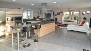 A modern kitchen with a central island, bar stools, and a dining table. - Lovely home in Saint-Gilles (Saint-Gilles)