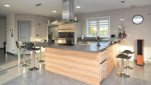 A modern kitchen with a central island, stainless steel appliances, and bar stools. - Lovely home in Saint-Gilles (Saint-Gilles)
