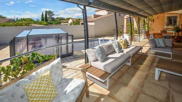 A covered outdoor seating area with a glass enclosure, a pool, and a view of surrounding buildings. - Lovely home in Saint-Gilles (Saint-Gilles)