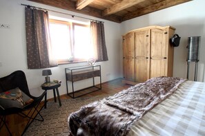 A bedroom with a bed, a wooden wardrobe, a desk with a lamp, and a chair. - Chalet Belle Kaiser by belle-stay (Sonnseite)
