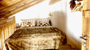 Un dormitorio con techo de madera, una cama con colcha cuadriculada y un armario de madera con un adorno colgante.