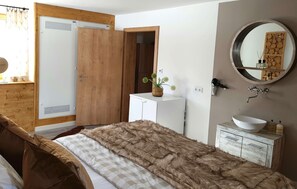 Ein Schlafzimmer mit einem Bett, einem Nachttisch, einem Spiegel, einer Kommode und einer Tür.
