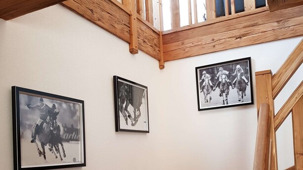 Una escalera de madera con tres fotografías blanco y negro enmarcadas en la pared.