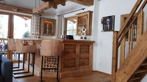 Un interior de madera con una zona de bar, vigas de madera en el techo y una escalera.