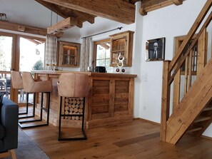 Ein Holzinnenraum mit Barbereich, Holzbalkendecke und einer Treppe.
