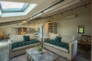 A modern living room with two sofas, a coffee table, and a skylight.
