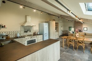 Une cuisine moderne dotée d’un îlot central, d’appareils électroménagers intégrés et d’un coin repas avec une table et des chaises en bois.