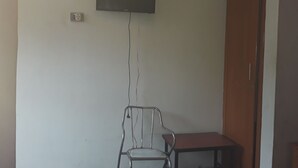 A room with a television mounted on the wall, a chair, and a small table.