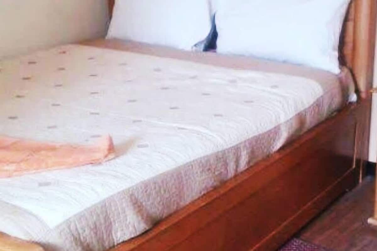 A single bed with a wooden headboard and white bedding.