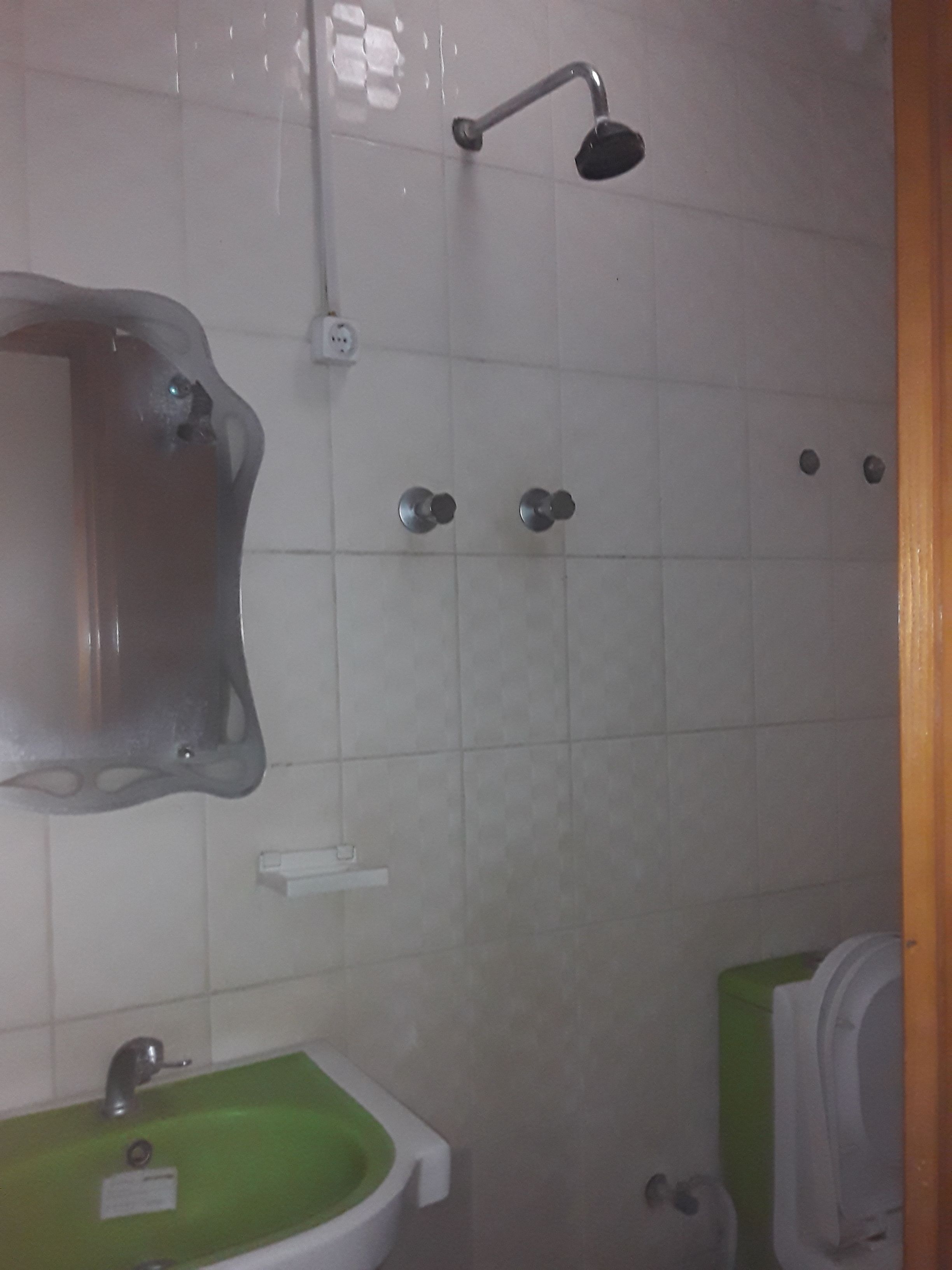A bathroom with a green sink, a shower, and a toilet.