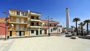 Um edifício costeiro com varandas, um farol e palmeiras.