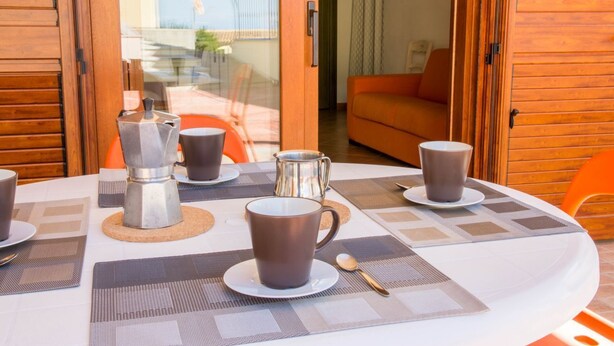 Une table à manger dressée avec des tasses à café, une cafetière et un sucrier.