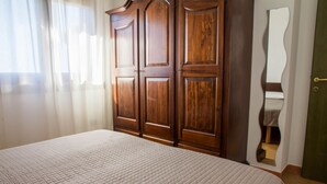 Ein Schlafzimmer mit Bett, Holzschrank und Spiegel.