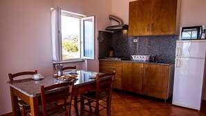 A compact kitchen with wooden cabinets, a granite countertop, and a white refrigerator. - SMART GROUND (badesi)