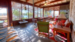 A spacious room with a large bed, wooden furniture, and a view through large windows. - Mesquite Creek Farmhouse (New Braunfels)