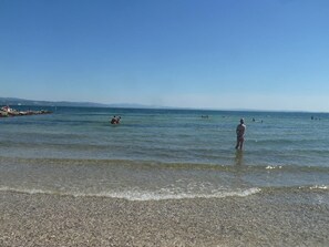 A beach with clear water, pebbly shore, and distant mountains. - La Finestra sul mare (Marina Julia, Monfalcone,Italy)