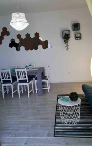 A dining area with a table and chairs, a hanging light fixture, and a patterned rug. - La Finestra sul mare (Marina Julia, Monfalcone,Italy)