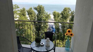 Ein Balkon mit Glastisch, Stühlen, einem kleinen Topfpflanzen und einer Vase mit Sonnenblumen.
