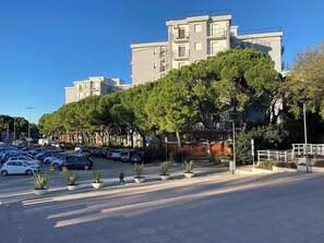 A parking lot with cars, a pedestrian walkway, and a building with balconies. - La Finestra sul mare (Marina Julia, Monfalcone,Italy)
