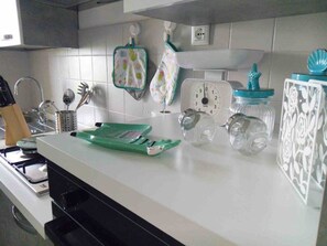 A kitchen with white cabinets, a stove, a green cutting board, and various kitchen utensils. - La Finestra sul mare (Marina Julia, Monfalcone,Italy)
