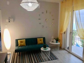A living room with a sofa, a round coffee table, a floor lamp, and a window with curtains. - La Finestra sul mare (Marina Julia, Monfalcone,Italy)