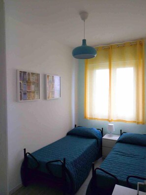 A small room with two single beds, a nightstand with a lamp, a ceiling light, and two wall-mounted paintings. - La Finestra sul mare (Marina Julia, Monfalcone,Italy)