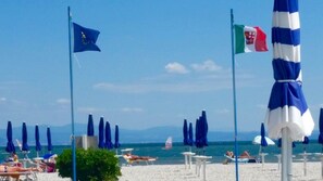A beach with flags, umbrellas, and people. - La Finestra sul mare (Marina Julia, Monfalcone,Italy)