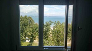 A room with a large window offering a view of a body of water and greenery. - La Finestra sul mare (Marina Julia, Monfalcone,Italy)