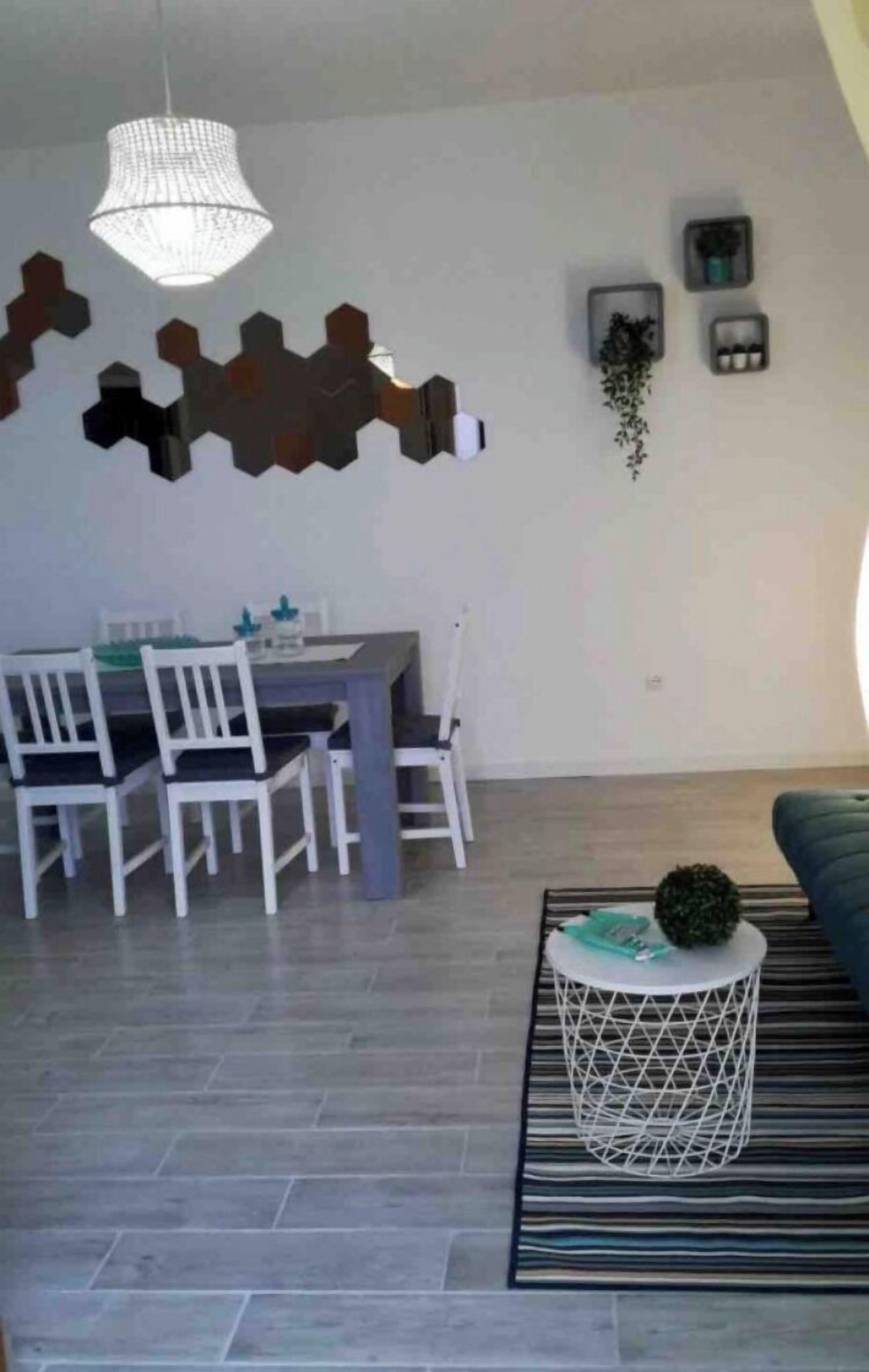 Ein Essbereich mit Tisch und Stühlen, einer Pendelleuchte und einem gemusterten Teppich.