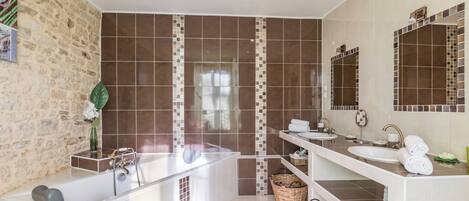 Une salle de bain moderne avec une baignoire, deux lavabos et un grand miroir.