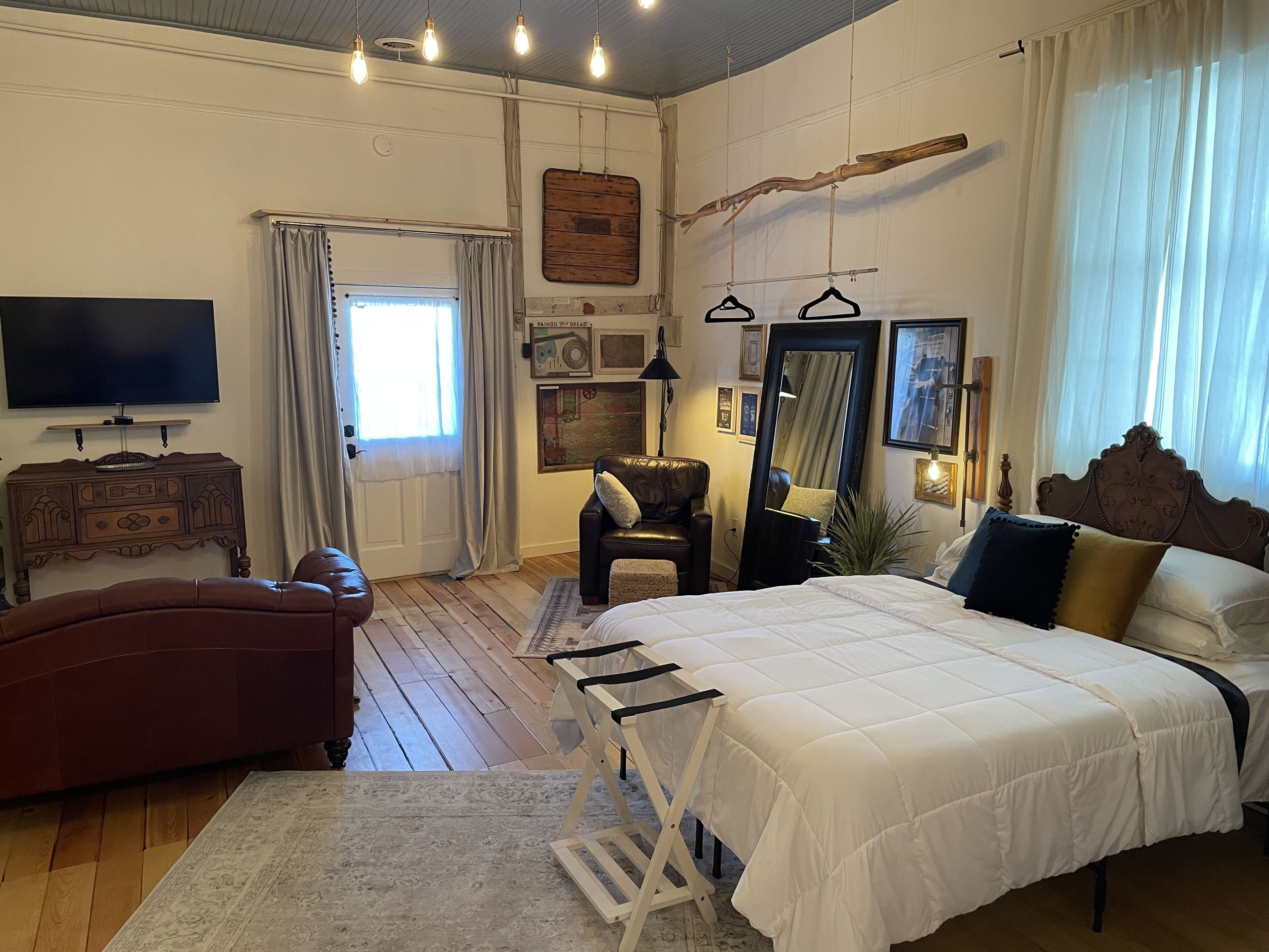 Ein Schlafzimmer mit einem großen Bett, einem Sofa, einem Fernseher und einer hölzernen Kommode.