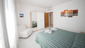 Ein Schlafzimmer mit Bett, Kleiderschrank, Spiegel und einem Bild an der Wand.