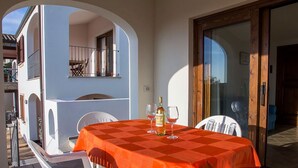 An outdoor dining area with a table set for two, a bottle of wine, and two glasses. - VIGNA SUPERIOR (Badesi)