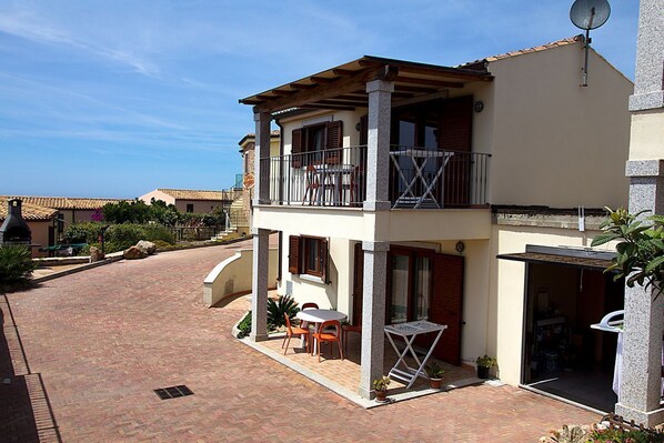 A two-story building with a balcony, a patio with outdoor furniture, and a satellite dish.