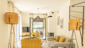 Ein Wohnzimmer mit einer Couch, einem Couchtisch, einer Stehlampe und einem Fernseher.