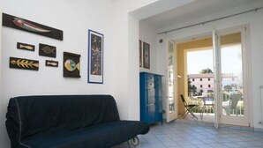 Een kamer met een zwarte bank, een blauwe kast en wanddecoratie, waaronder vismotieven en een ingelijste foto.