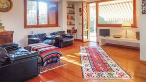 A living room with leather sofas, a patterned rug, a television, and a bookshelf. - Panoramic villa surrounded by greenery with swim.pool and gym 5' from the beach. (Montesecco)