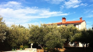 A building with a red roof, surrounded by dense greenery and trees. - Panoramic villa surrounded by greenery with swim.pool and gym 5' from the beach. (Montesecco)