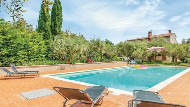 A swimming pool with lounge chairs and a garden area. - Panoramic villa surrounded by greenery with swim.pool and gym 5' from the beach. (Montesecco)