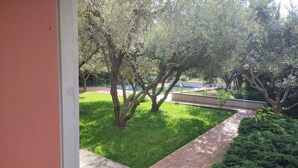 A view of a garden with a paved pathway, green grass, and trees. - Panoramic villa surrounded by greenery with swim.pool and gym 5' from the beach. (Montesecco)