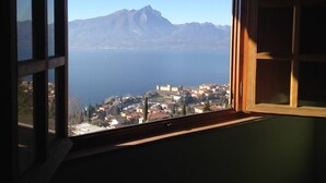 A view from a window overlooking a town with a mountain in the background. - Villa Margiò (Torri del Benaco)