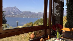 A room with a large window offering a view of a lake and mountains. - Villa Margiò (Torri del Benaco)
