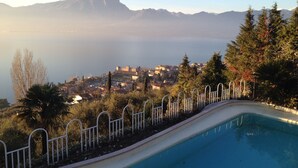 A swimming pool with a view of a town and mountains in the background. - Villa Margiò (Torri del Benaco)