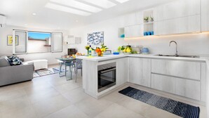 A modern kitchen with a central island, built-in oven, and a large window overlooking a balcony.