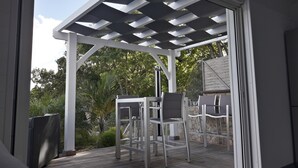 Alpendre coberto com pérgola, duas mesas e cadeiras.