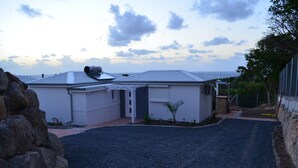 Uma casa com calçada de cascalho, antena parabólica e vista para o oceano.